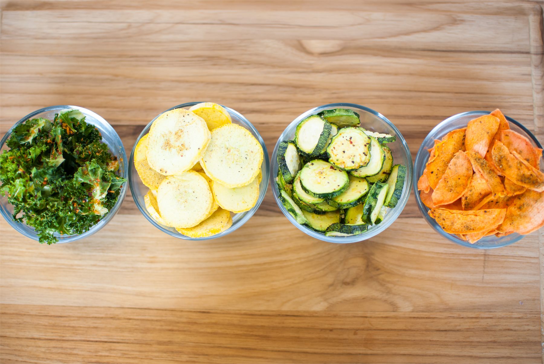 Bowls of sliced squash, carrots and leafy greens